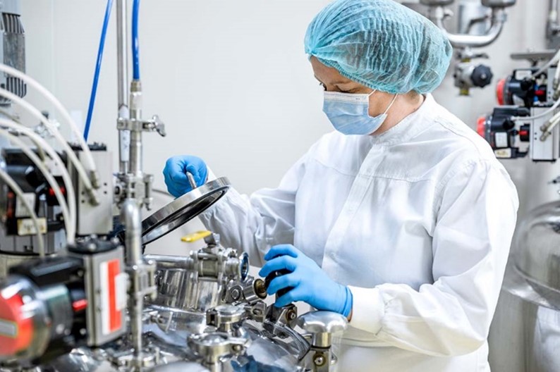 A technician preparing a batch in GMP-compliant facility for early-phase clinical trials